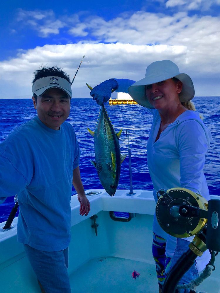A man is fishing on a boat in the ocean at sunset.