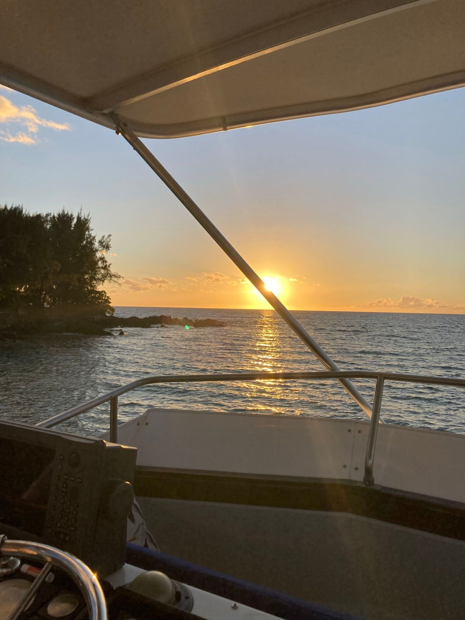 The sun is setting over the ocean from a boat