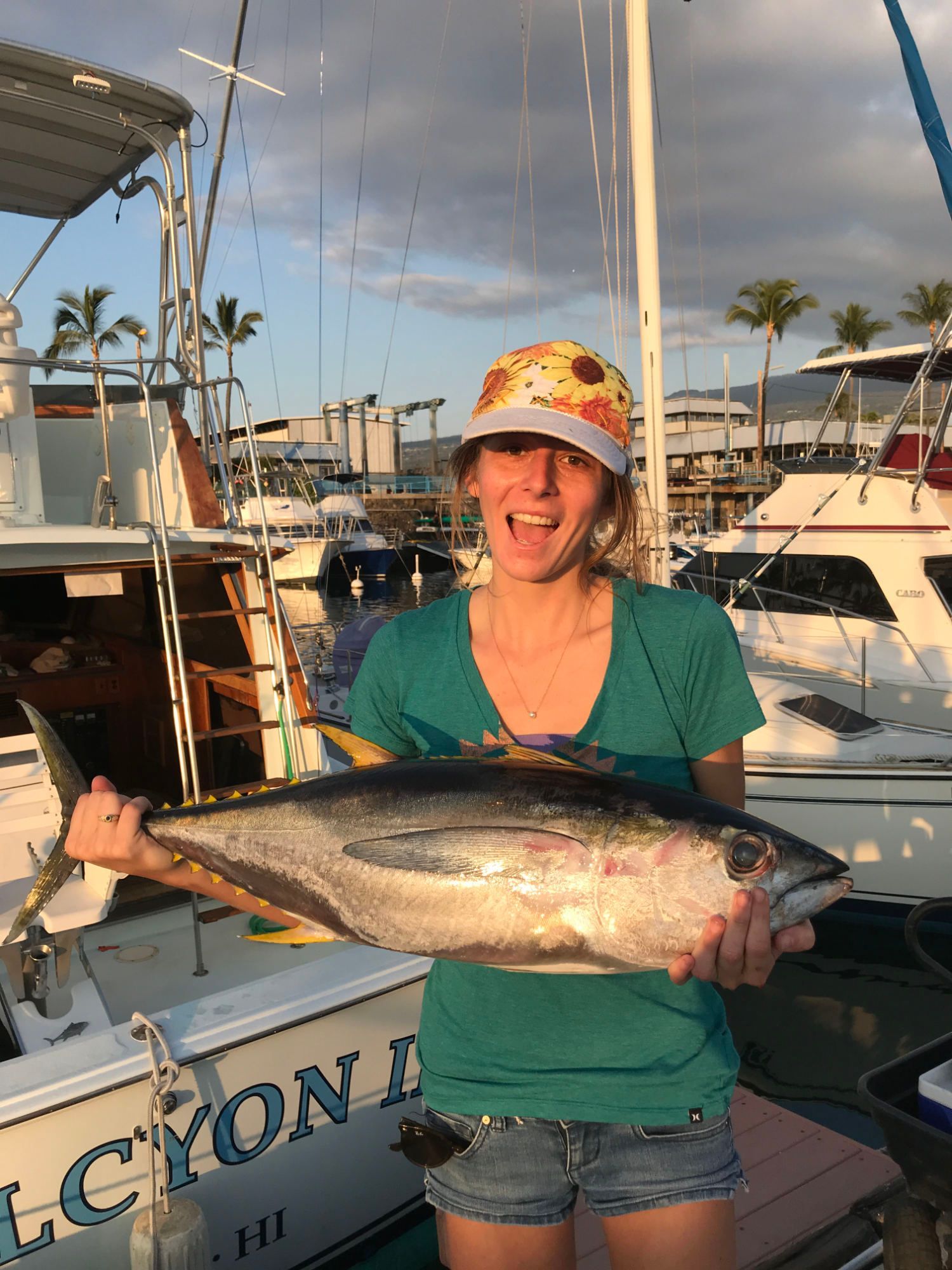 A woman is sitting at the helm of a boat in the ocean.