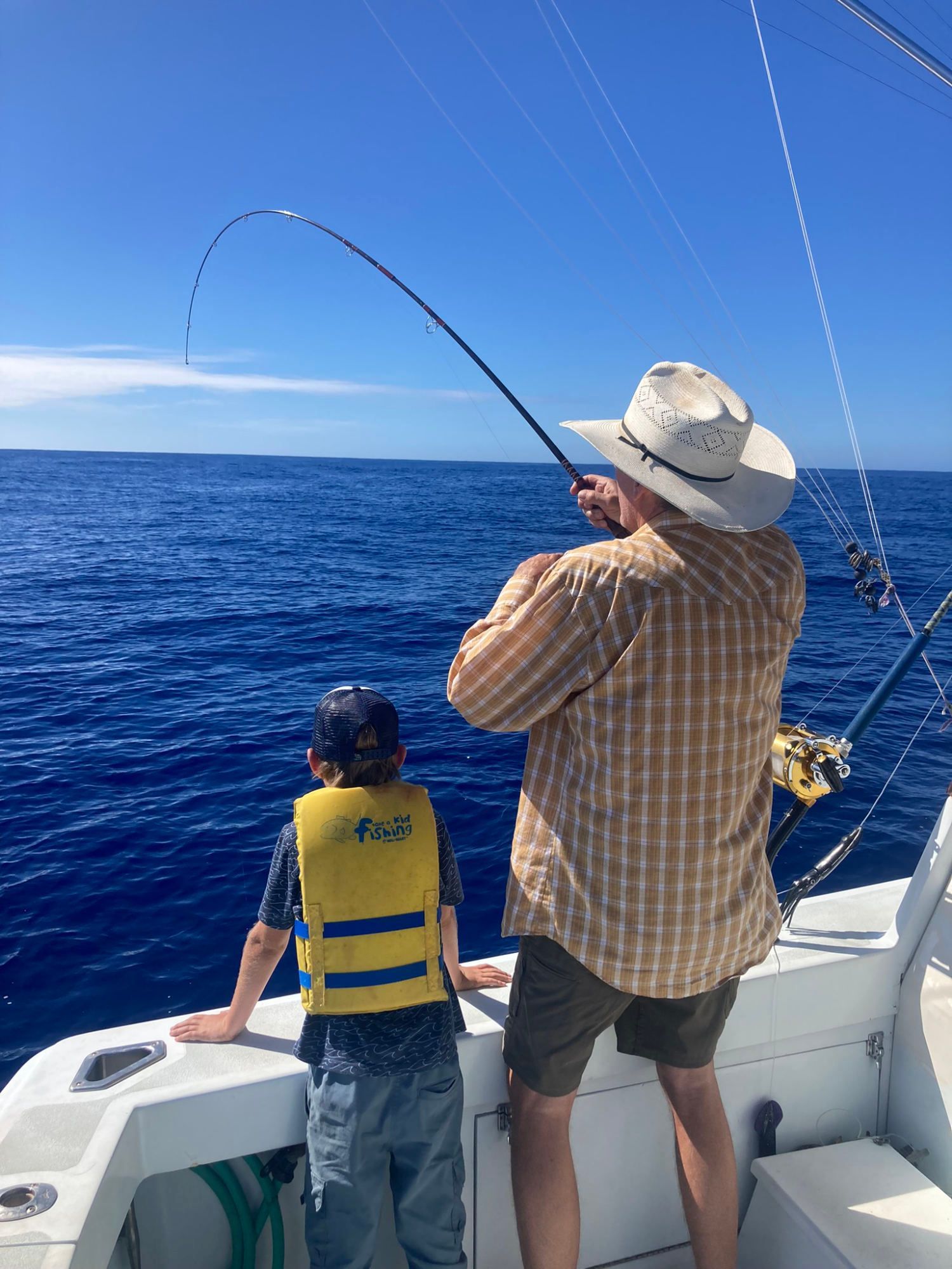 A man and a boy are fishing on a boat in the ocean.