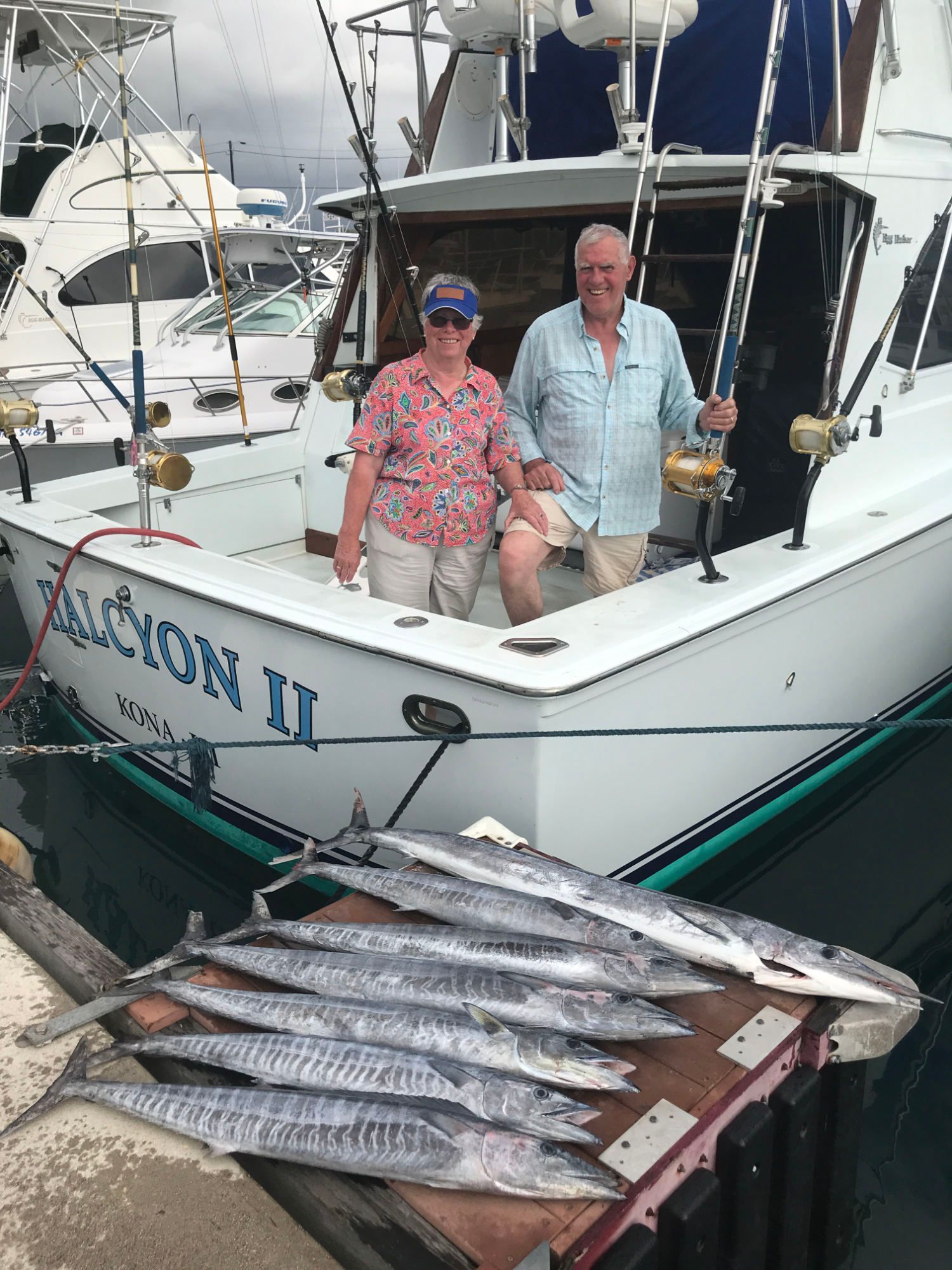 A man is sitting on a boat in the ocean wearing sunglasses and a hat.