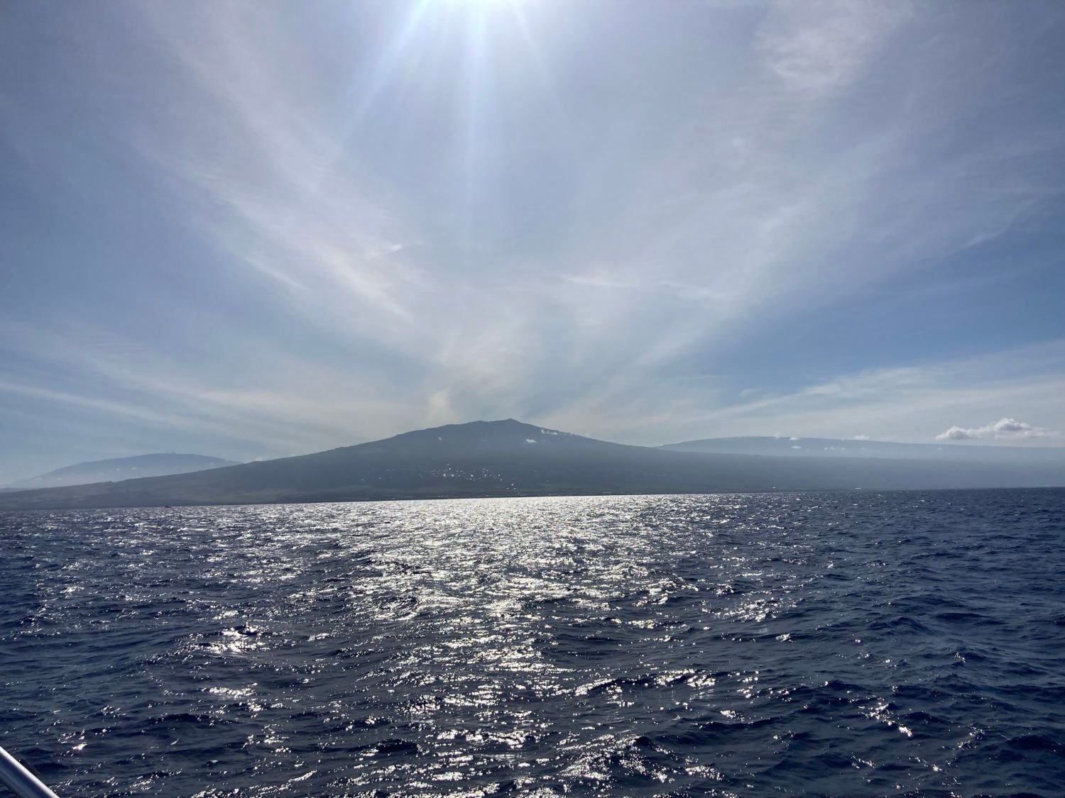 A man and a woman are standing on the back of a boat in the ocean.