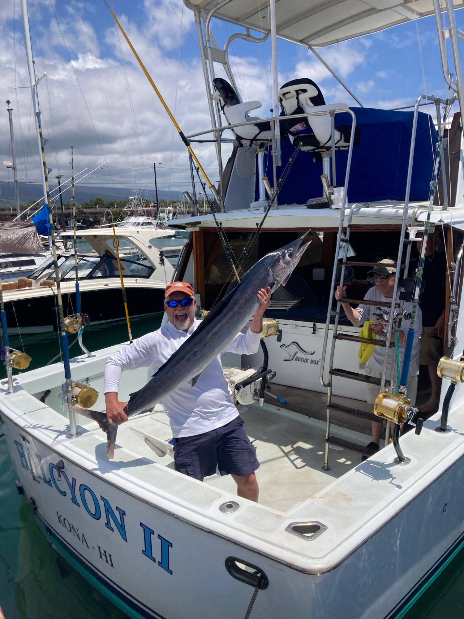 A man is standing on a boat holding a large fish.