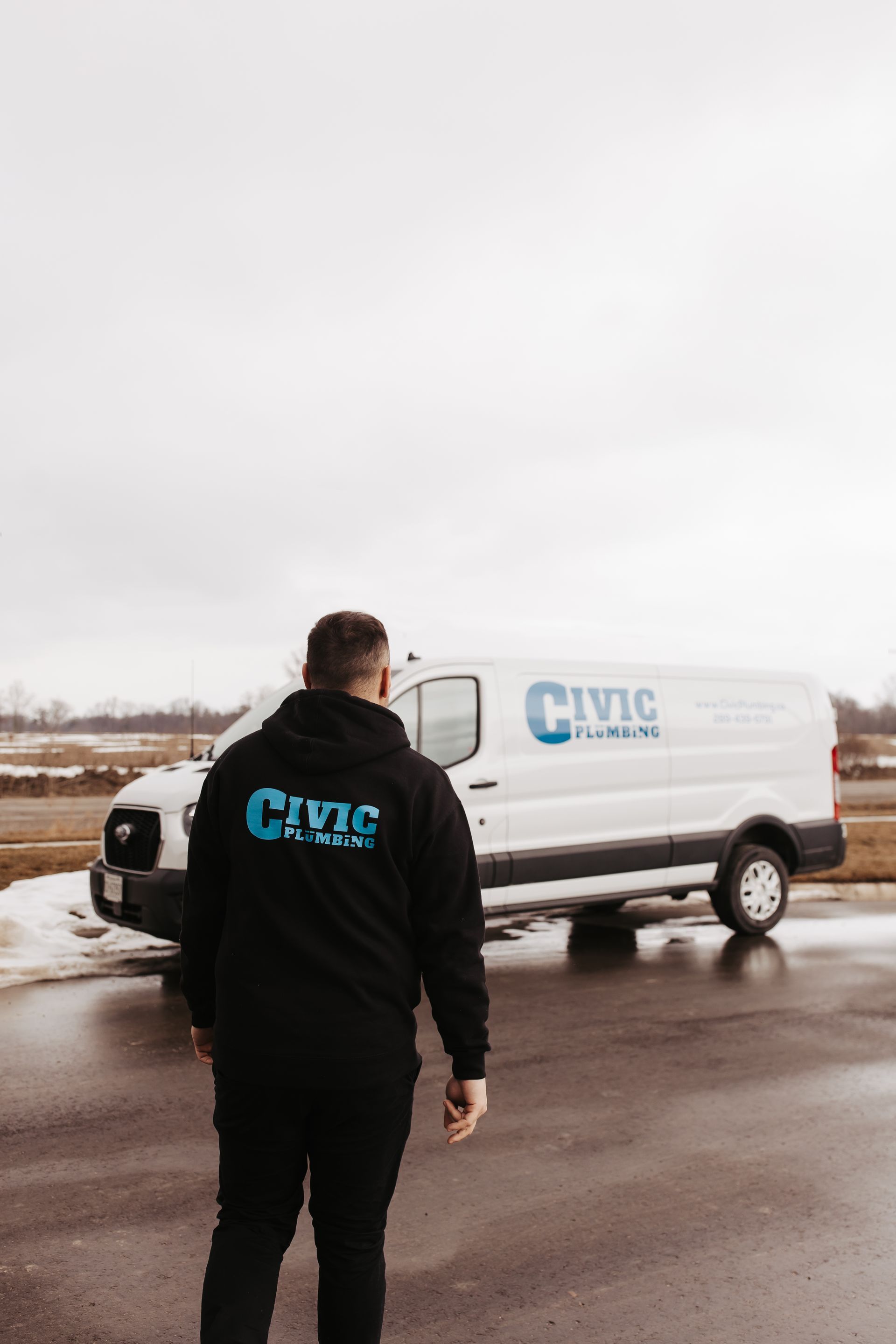 Man in black hoodie stands by a white van with 