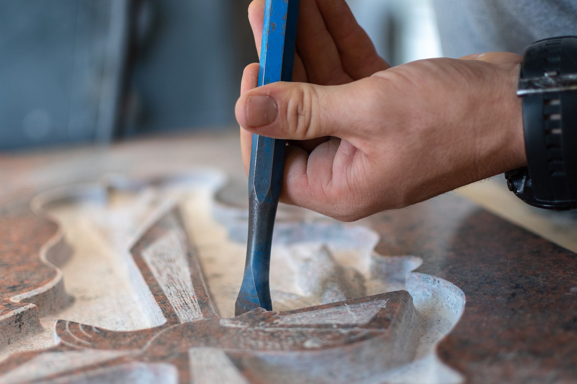a person is carving a design into a piece of stone with a chisel .