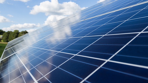 Solar panels reflecting the blue sky and clouds, installed outdoors.