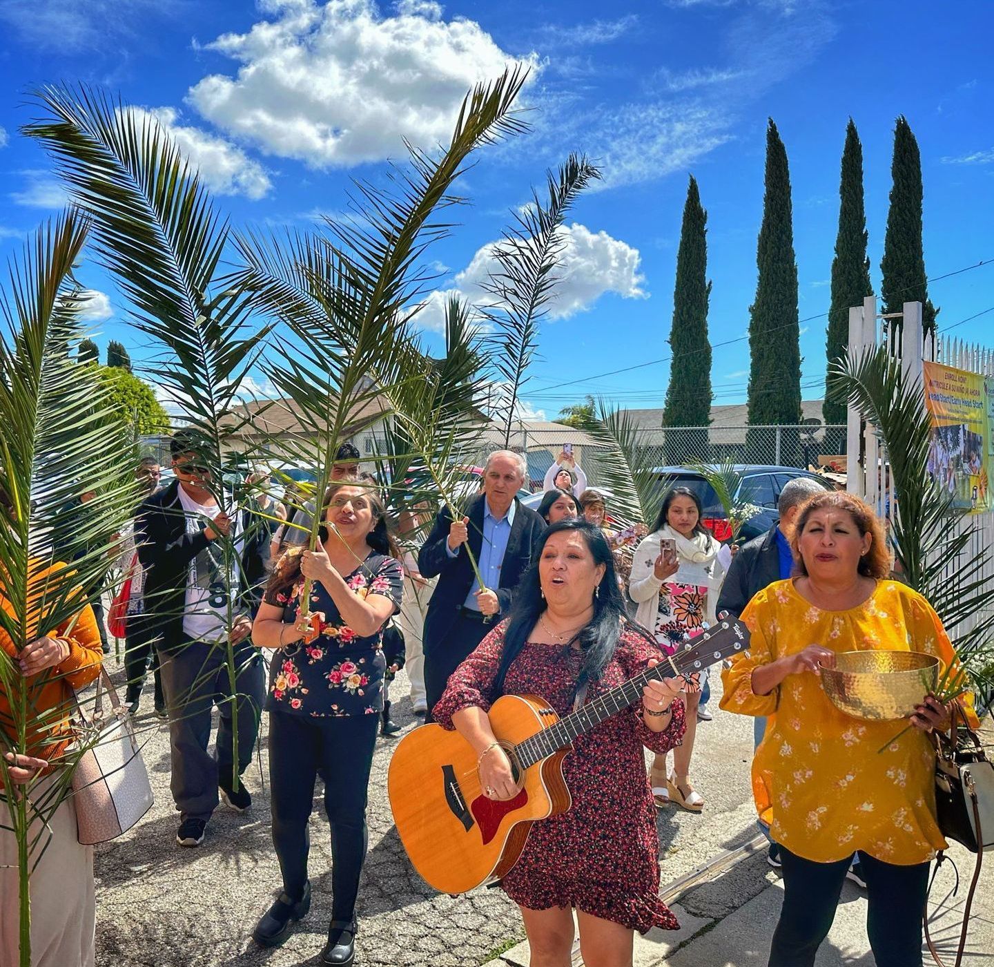 A woman is holding a guitar in front of a crowd of people