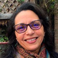 A woman wearing glasses and a scarf is smiling for the camera.