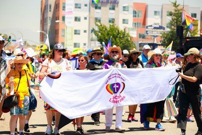 A group of people are walking down a street holding a large white flag.