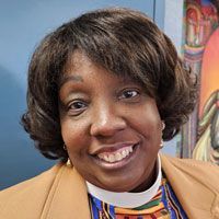 A close up of a woman wearing a brown jacket and smiling.