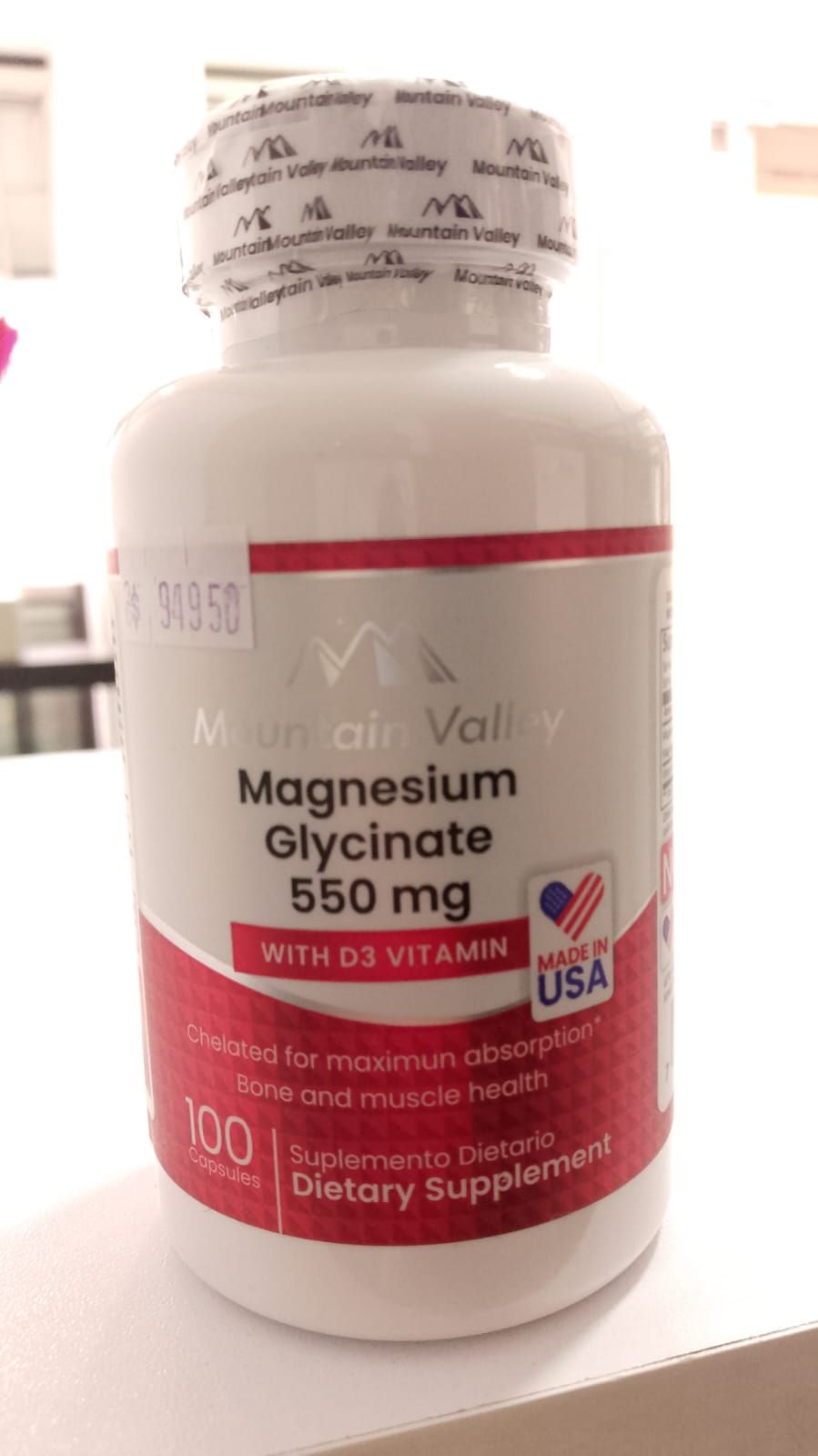 Una botella de glicinato de magnesio de 550 mg está sobre una mesa.