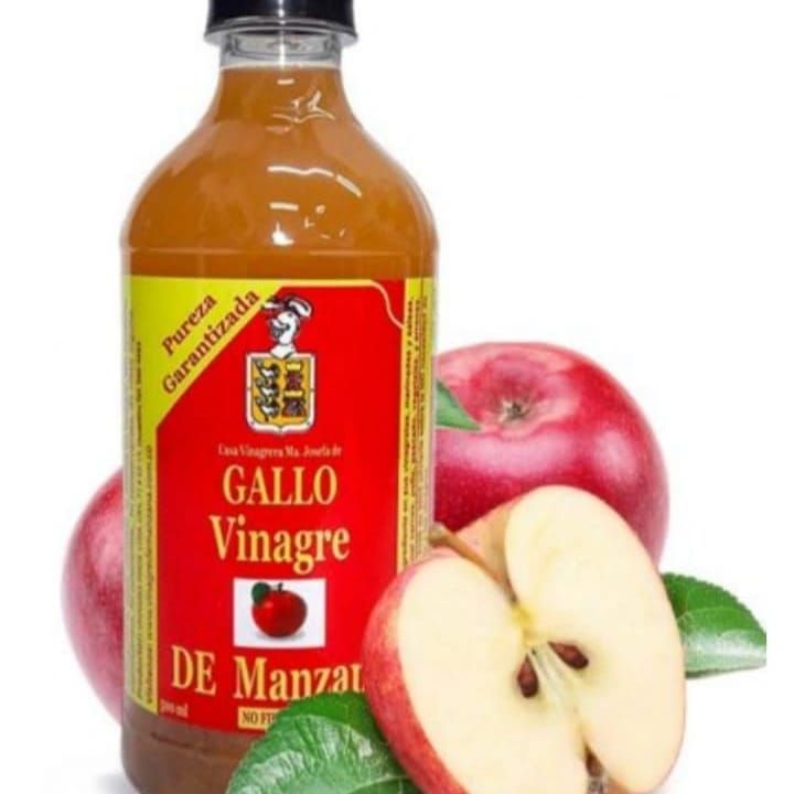 Una botella de gallo vinagre de manzana junto a manzanas