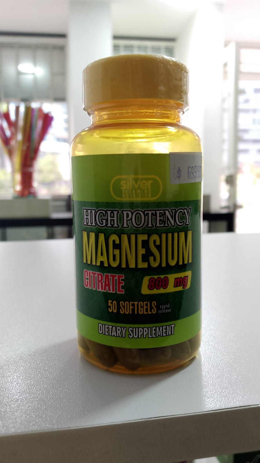 Una botella de pastillas de magnesio está sobre una mesa blanca.