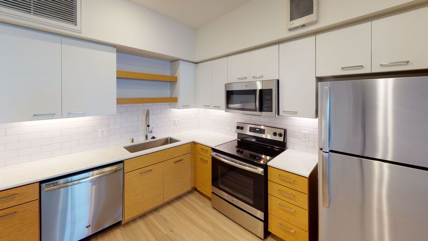 Modern kitchen with stainless steel appliances, white and wood cabinetry, and white backsplash.