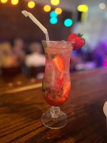 A drink with strawberries in it is on a table