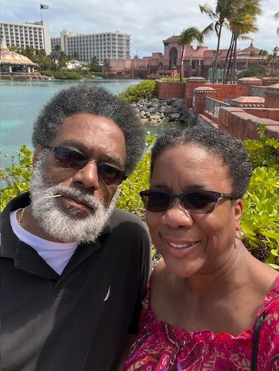 A man and a woman are posing for a picture in front of a body of water.