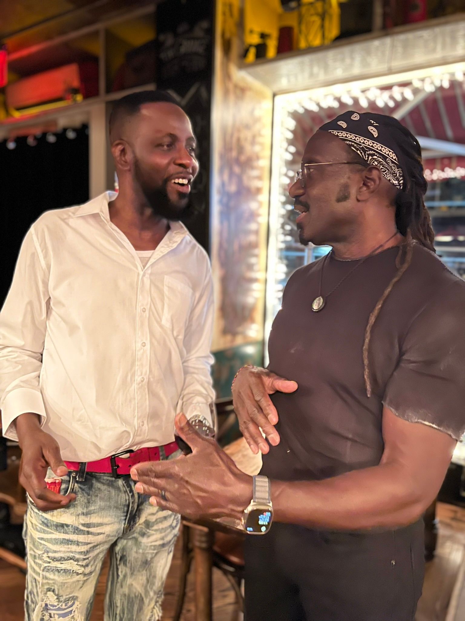 Two men are standing next to each other and talking in a room.