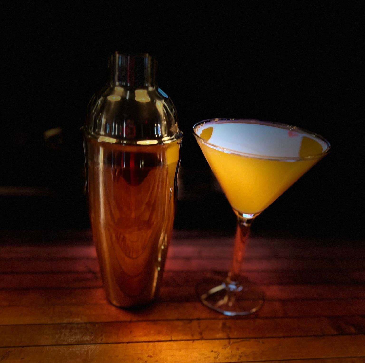 Two drinks are sitting on a table in front of a fireplace.