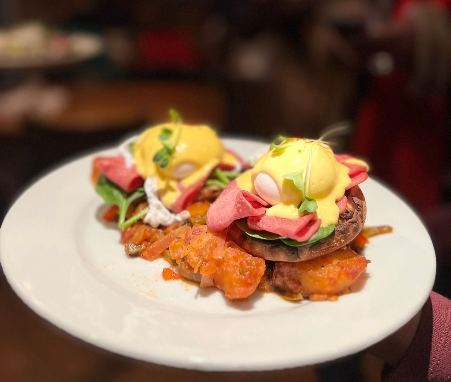 Two cocktails are sitting on a wooden bar next to each other.