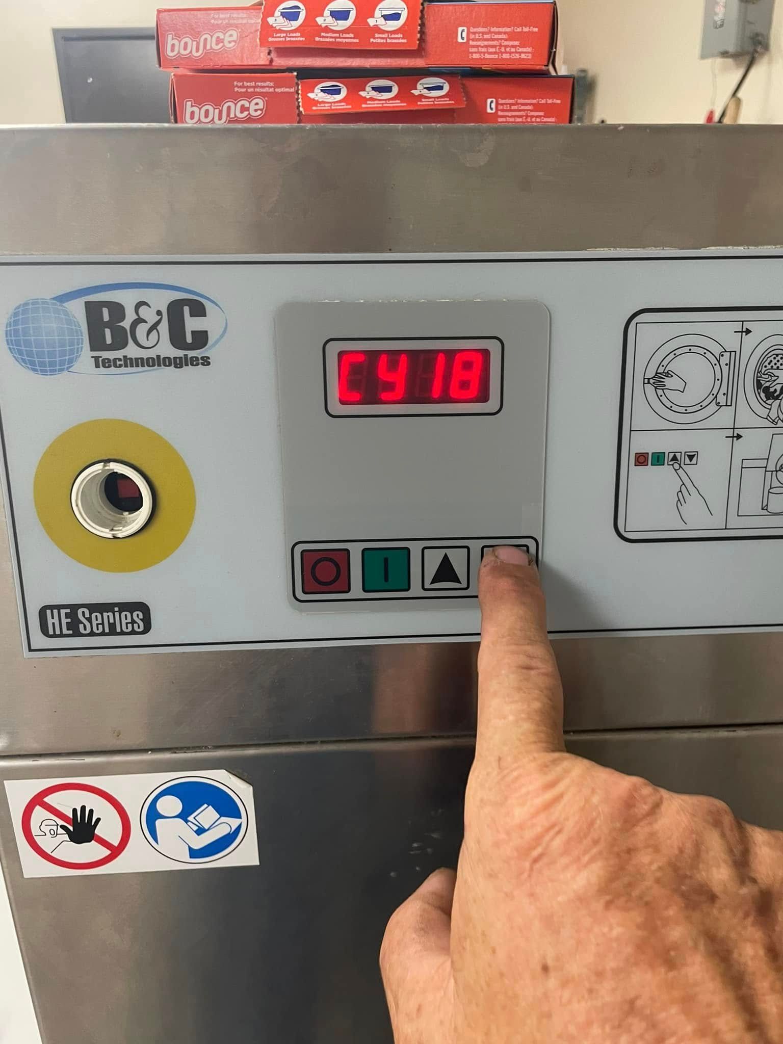 Hand pressing a button on a machine with a digital display showing 