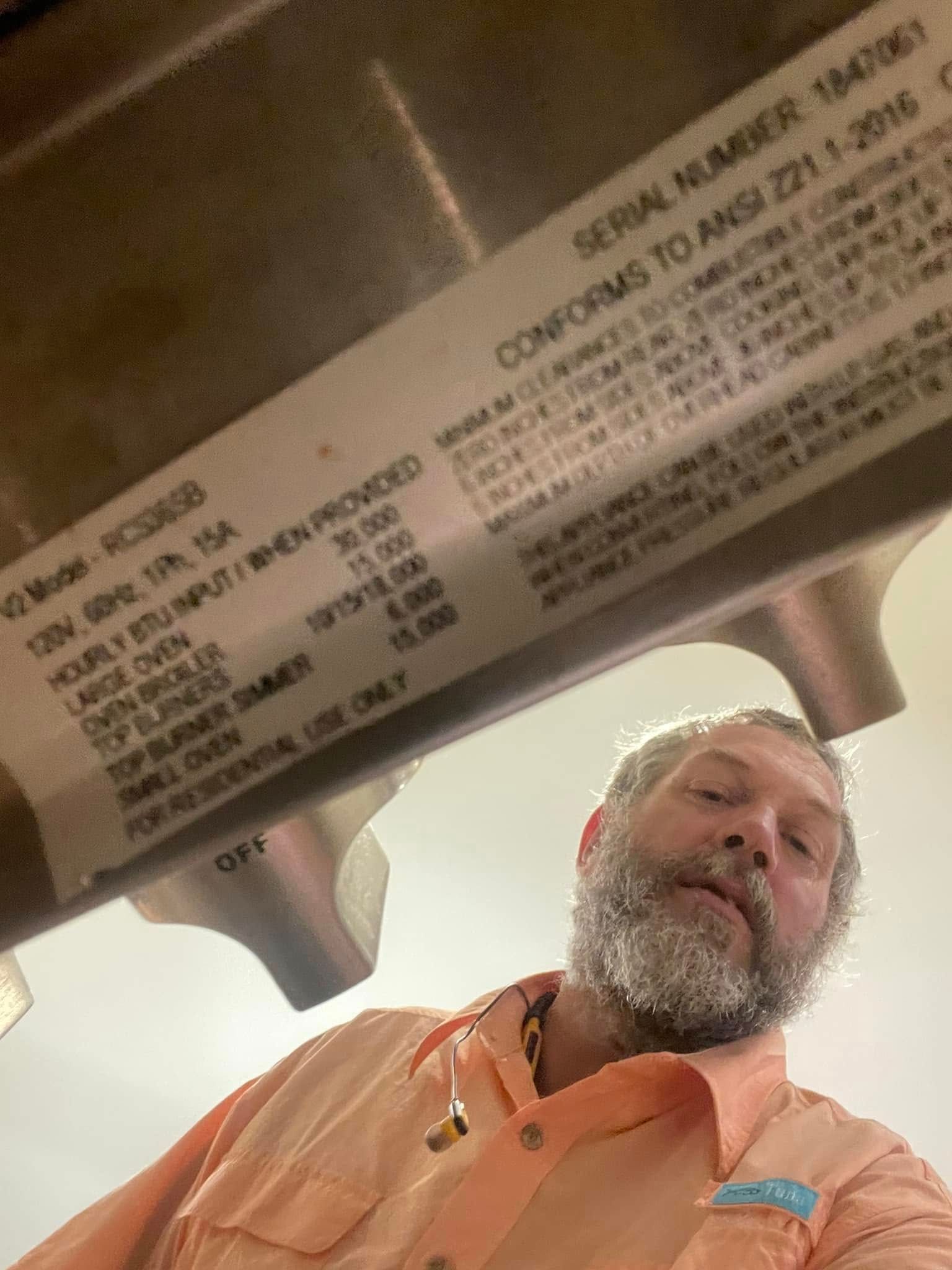 Man looking at an appliance label. The label has text, likely specifications.