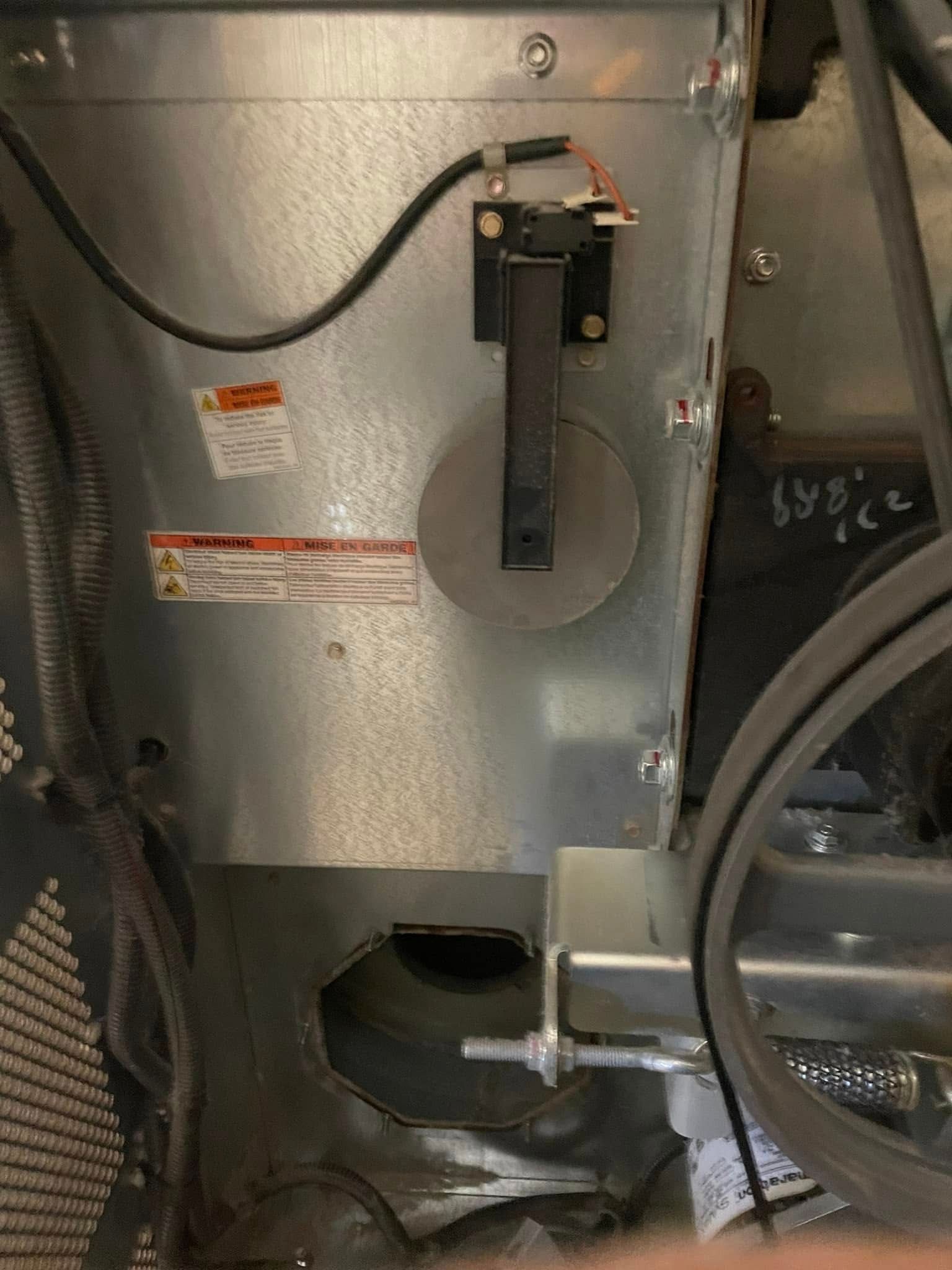 HVAC unit interior; round damper, black switch, belt, and metal housing.