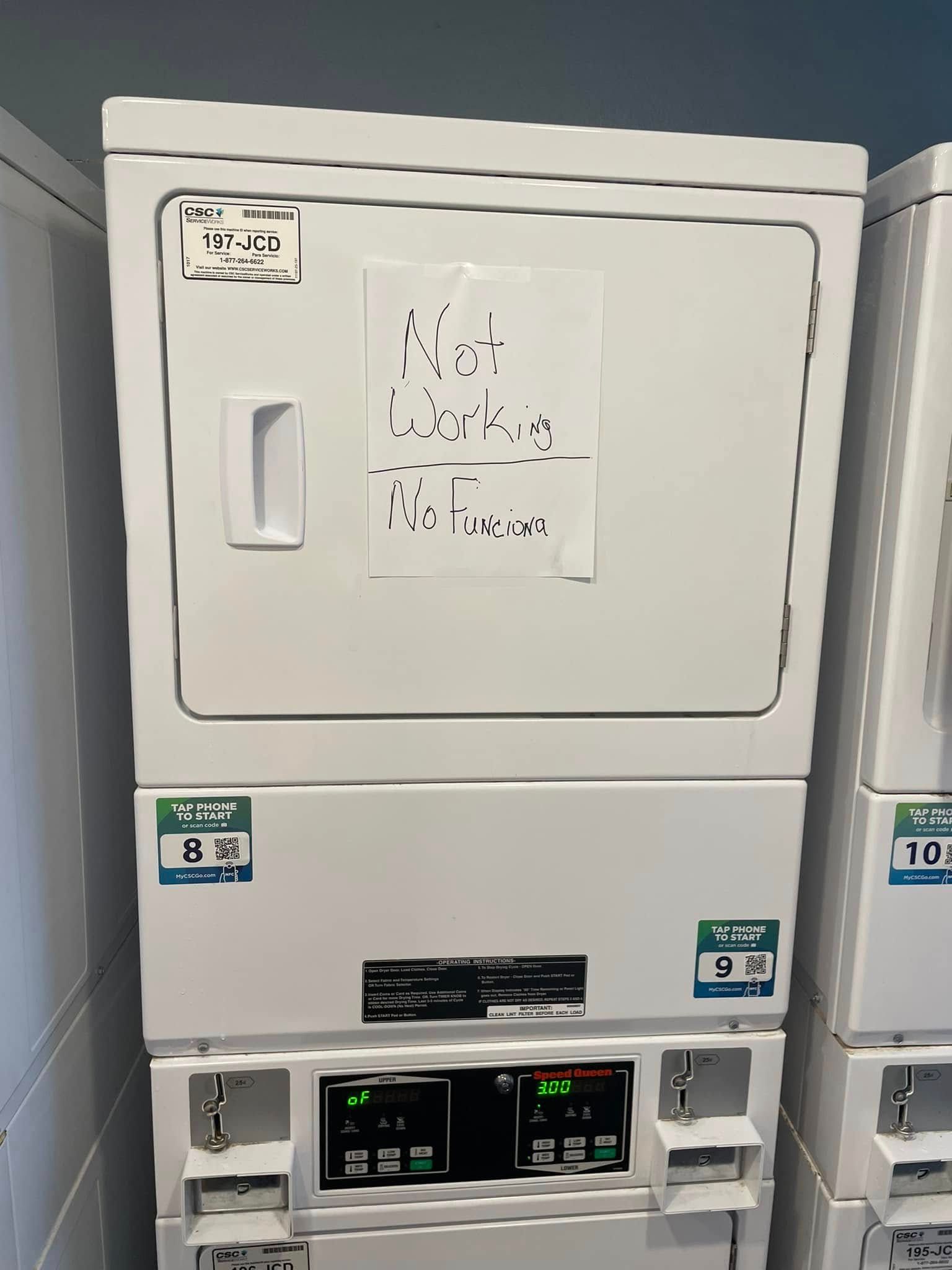 White stacked commercial laundry machine in a laundry room, with control panel.