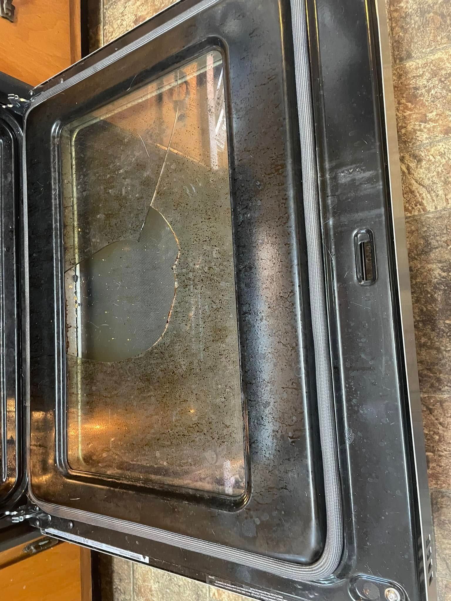 Open oven door with dirty glass and black frame.