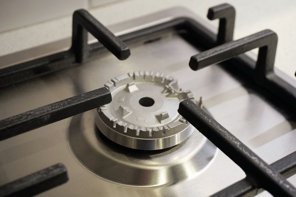 Close-up of a stainless steel gas stove burner with black grates.