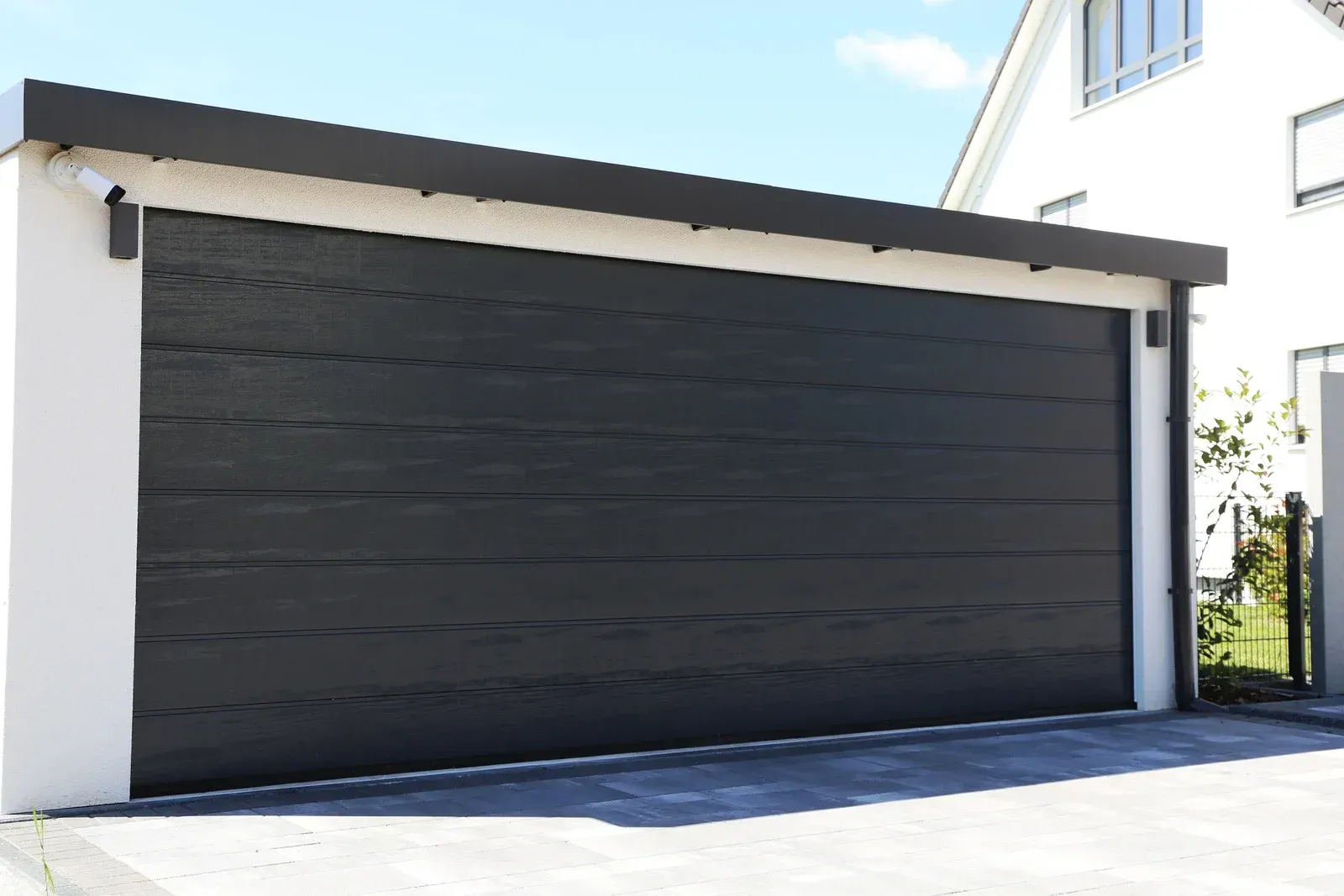 Black garage door on white building under a dark roof.