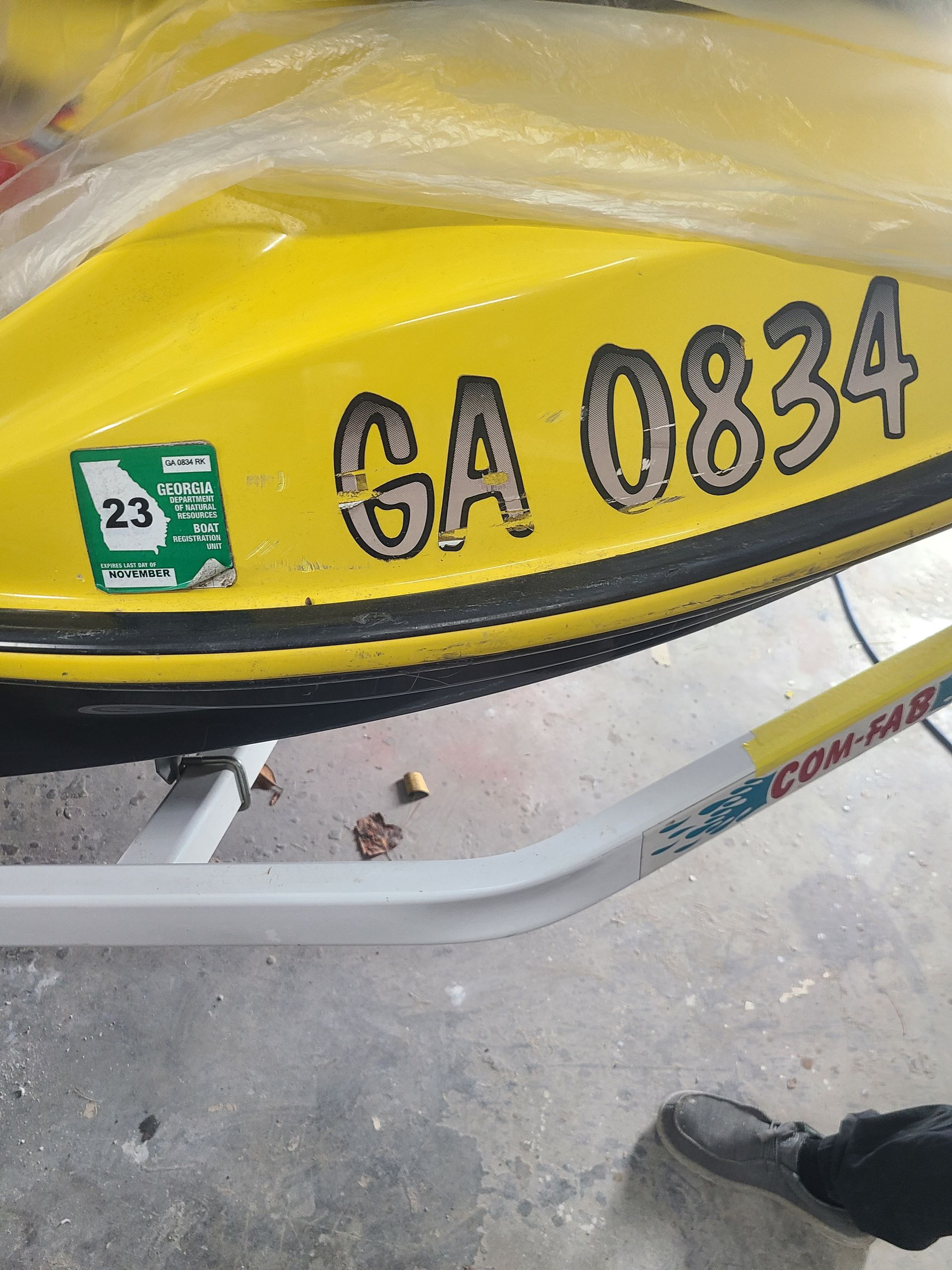 A bright yellow jet ski hull with the registration 