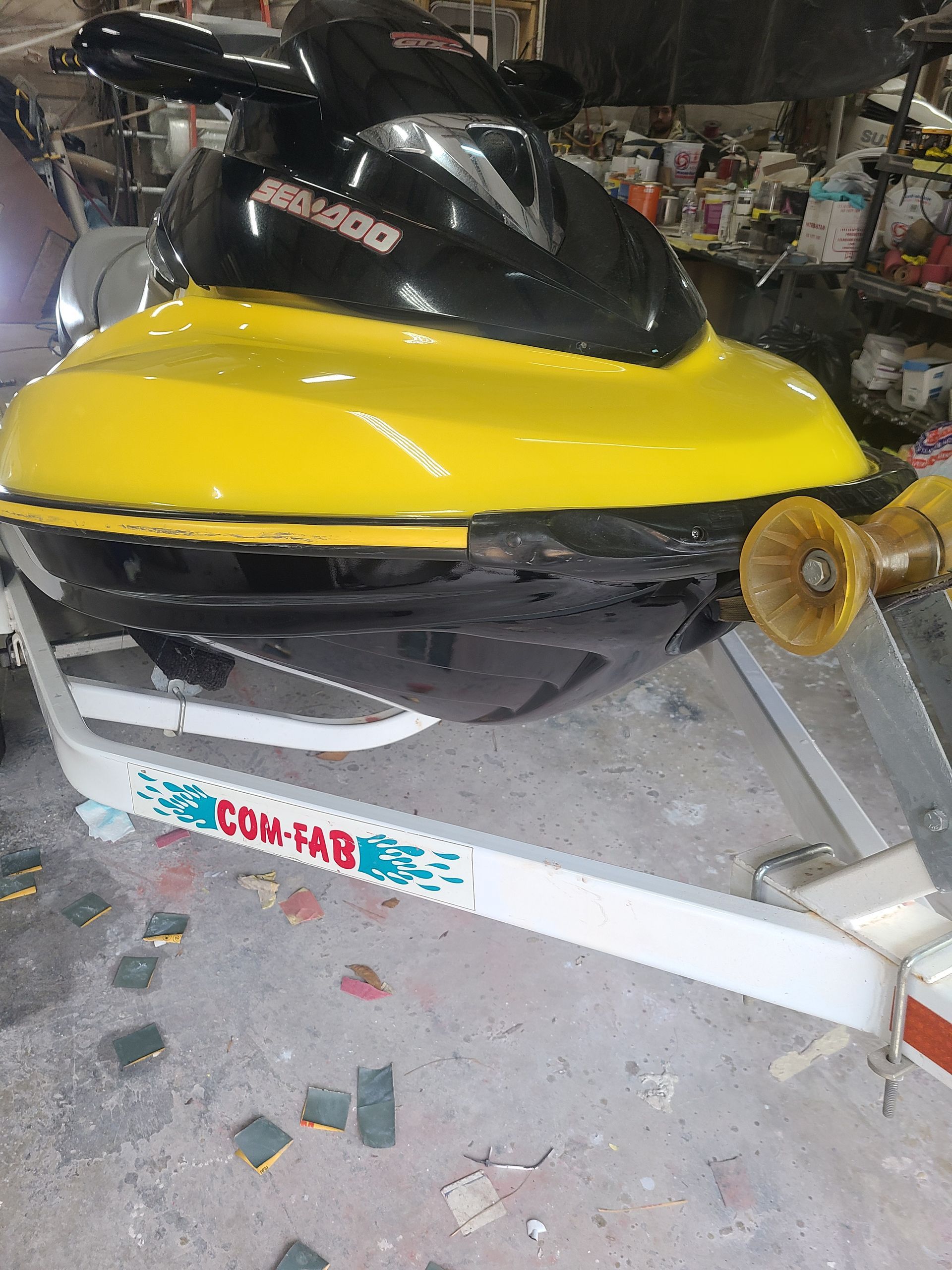 A yellow and black Sea-Doo personal watercraft sits on a white trailer in a garage or workshop.