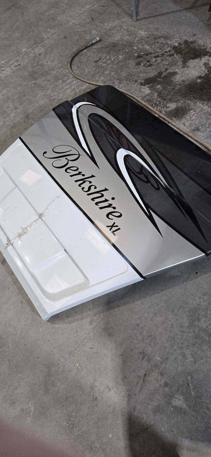 A white and black Berkshire XL RV fiberglass exterior panel resting on a concrete floor.