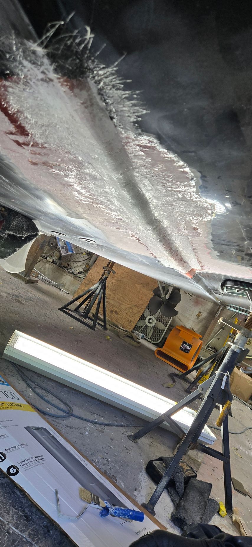 A low-angle shot of a car's undercarriage in a garage, showing a freshly applied layer of rust-proofing coating.