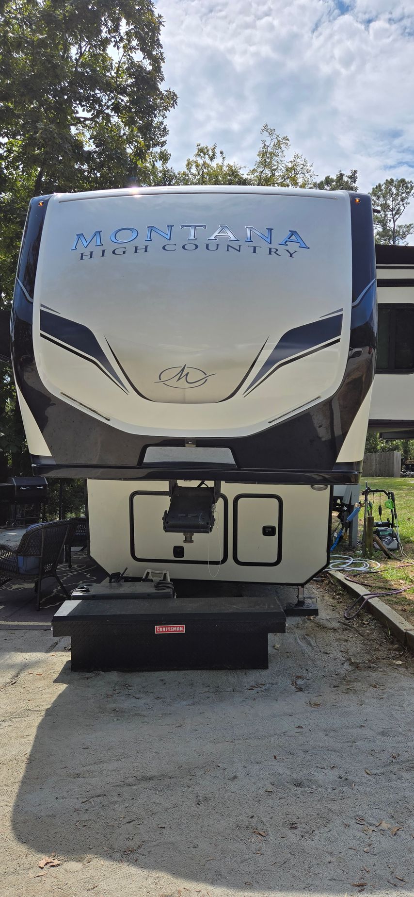 A Montana fifth-wheel travel trailer parked on a concrete surface, featuring white and black exterior styling.