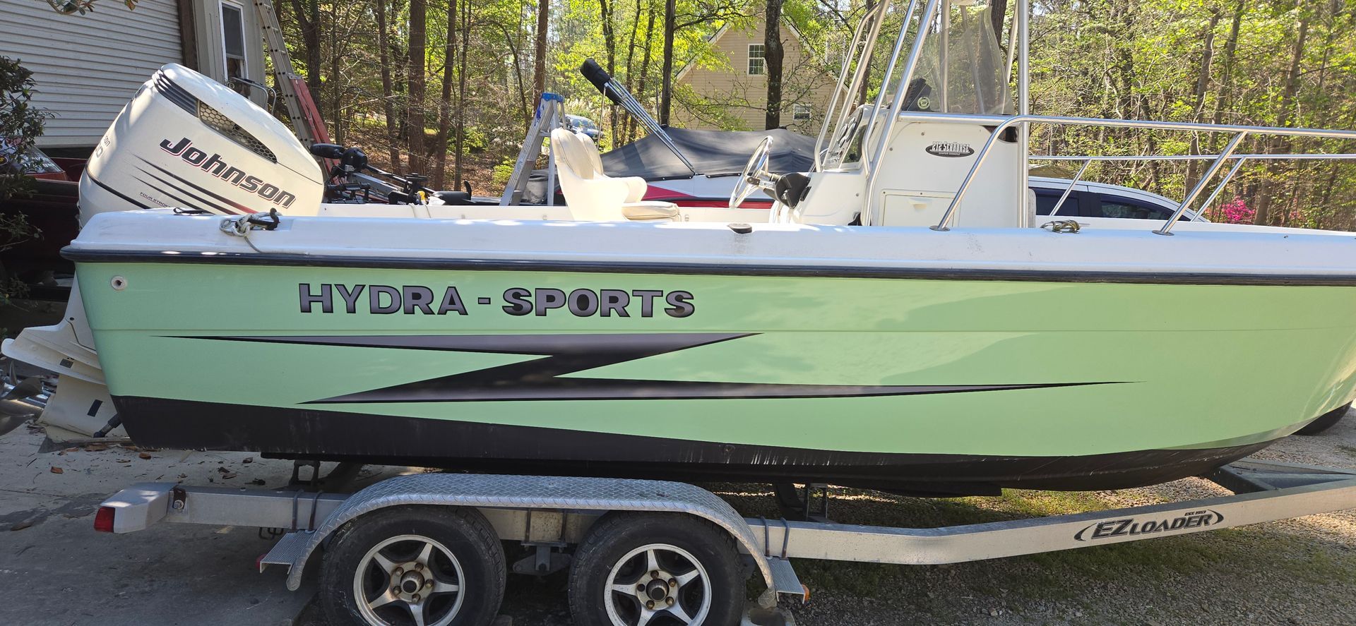 A light green Hydra-Sports center console boat with a Johnson outboard motor, parked on a boat trailer.