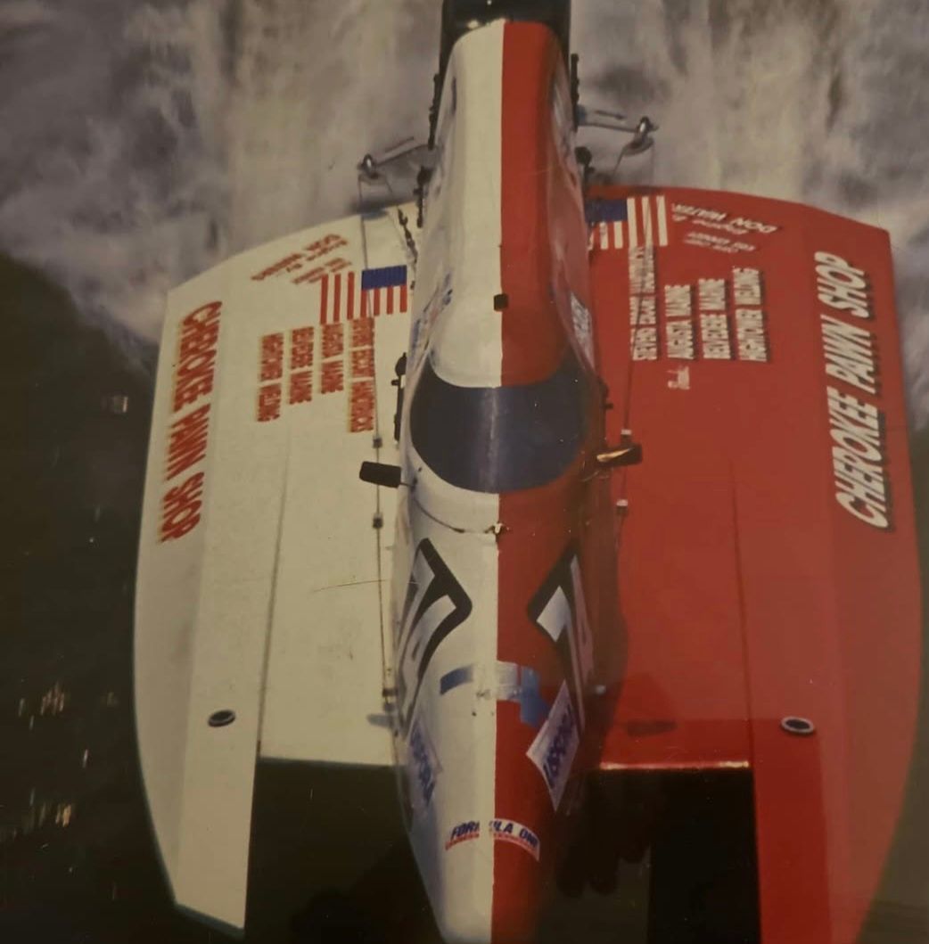 Top-down view of a red and white Cherokee Pawn Shop racing hydroplane boat speeding across the water.