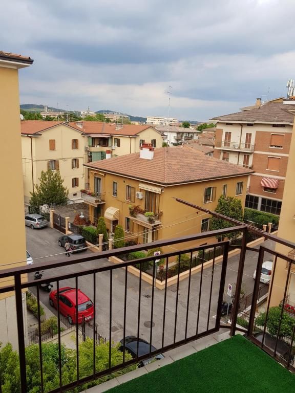 Vista da un balcone di edifici residenziali e auto parcheggiate sotto un cielo nuvoloso.