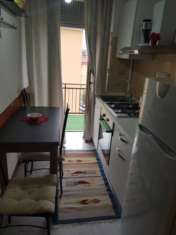 Piccola cucina con tavolo, porta finestra e frigorifero.