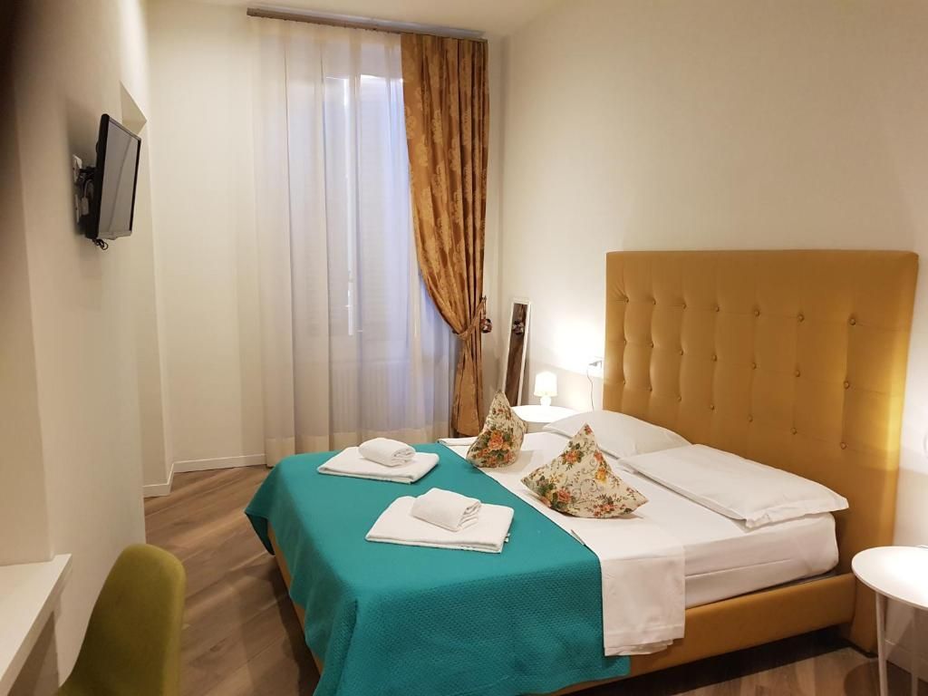 Camera da letto con testiera imbottita gialla, copriletto turchese, asciugamani bianchi e tende.