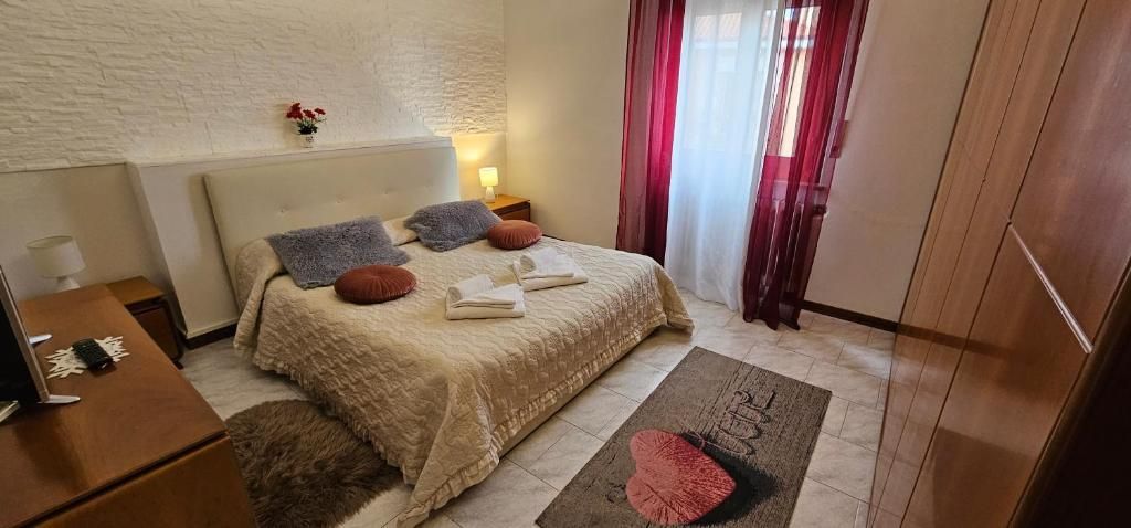 Camera da letto con letto, cuscini e tende rosse.