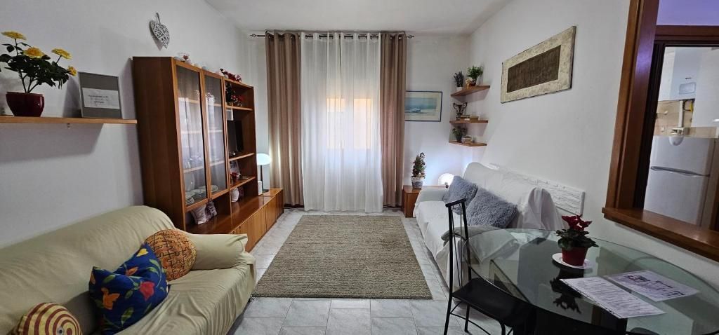 Soggiorno con mobili in legno marrone, due divani beige, un tappeto e un tavolo da pranzo.