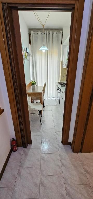 Vista attraverso una porta su una zona pranzo con tavolo, sedie e cucina.