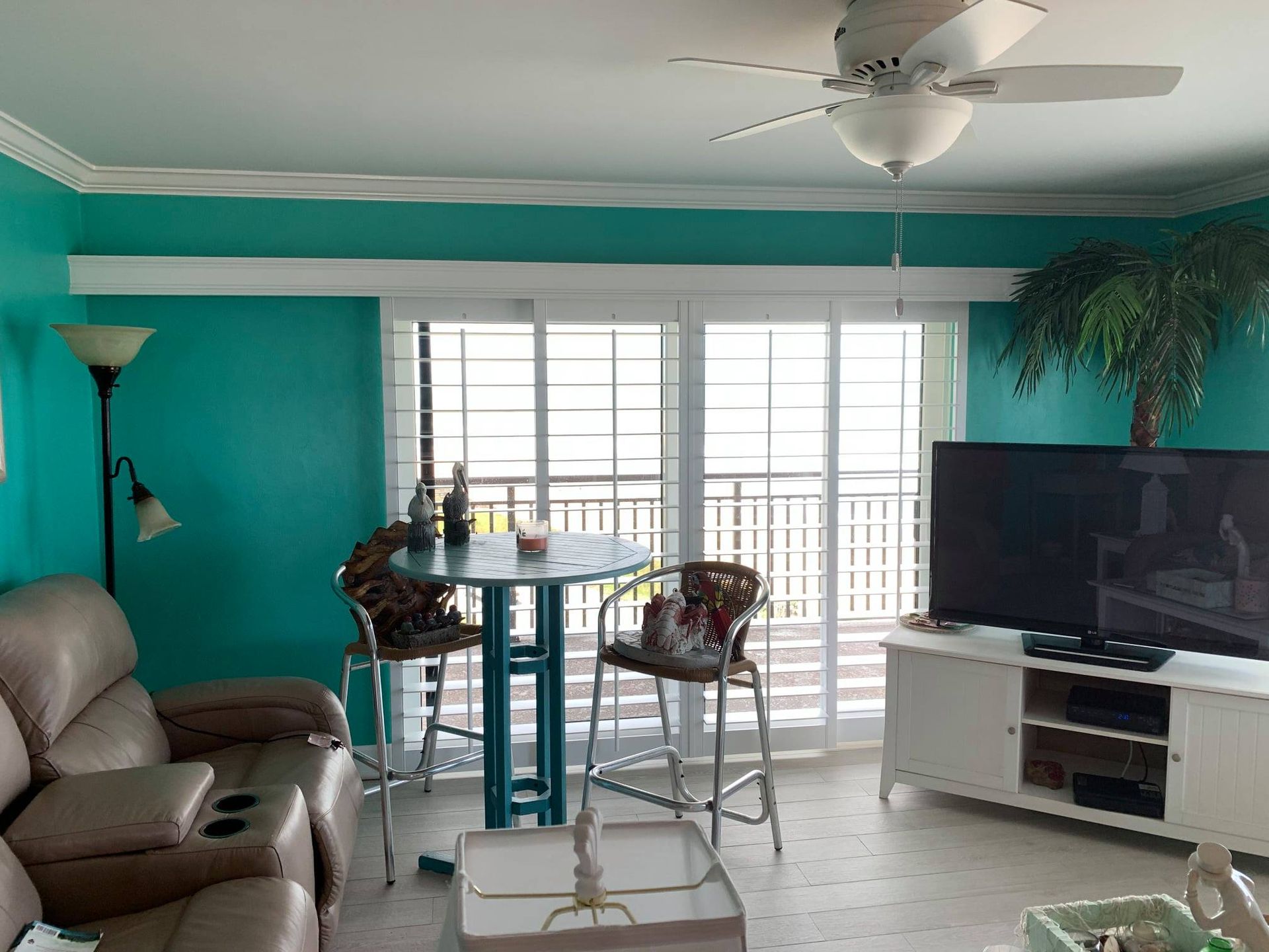 A living room with green walls and a ceiling fan — Deland, FL — Island Shutter Company