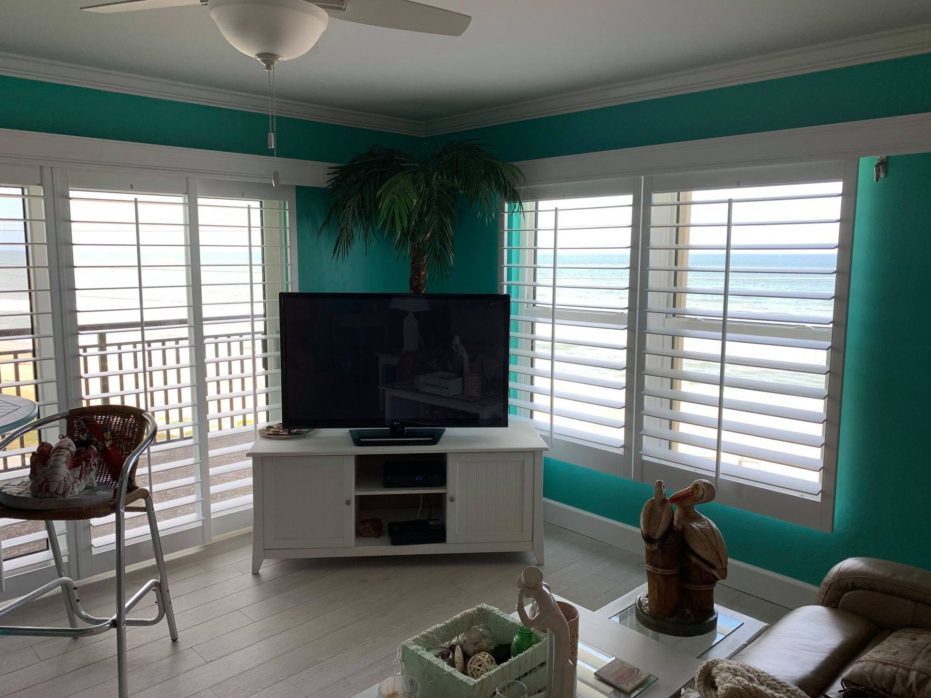 A living room with a flat screen TV and shutters on the windows — Deland, FL — Island Shutter Company