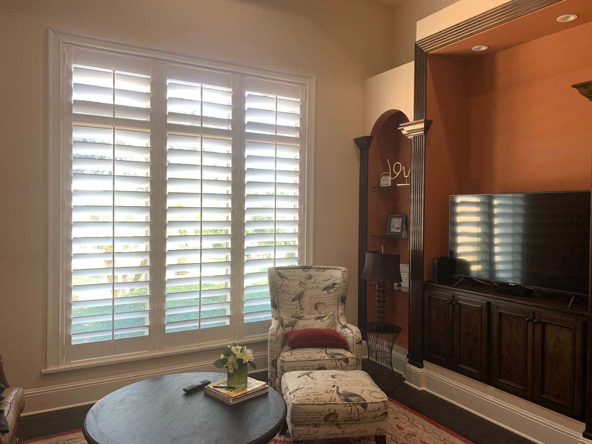 A living room with a chair, ottoman, table and television — Deland, FL — Island Shutter Company