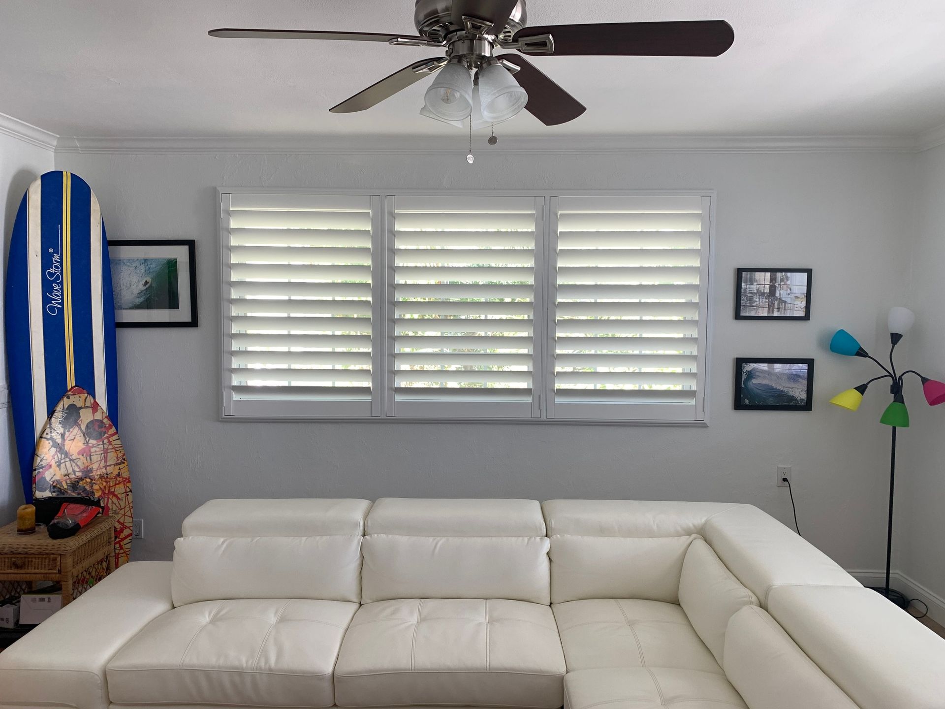 A living room with a couch, surfboard and a ceiling fan — Deland, FL — Island Shutter Company