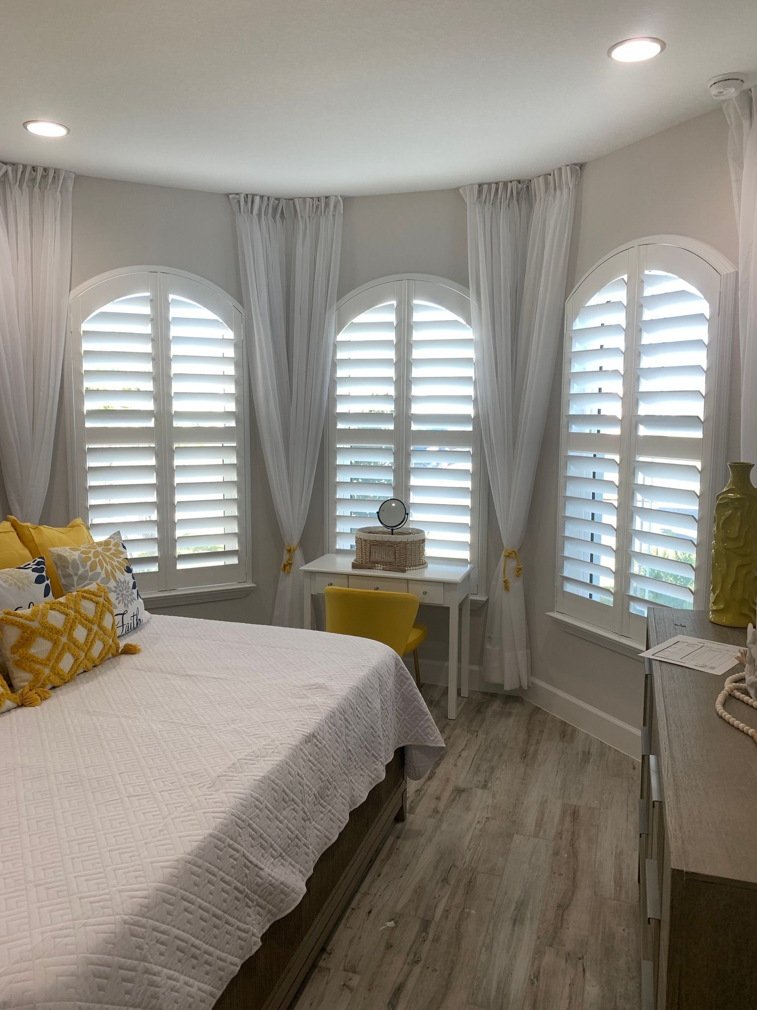 A bedroom with a bed, desk and shutters on the windows — Deland, FL — Island Shutter Company
