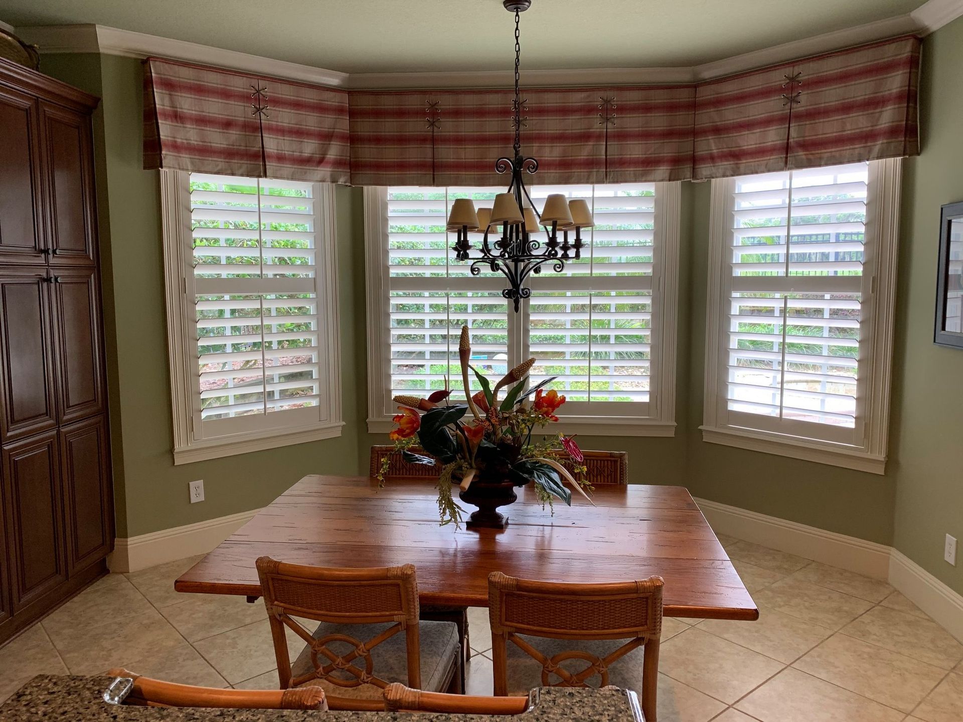 A dining room with a wooden table, chairs and a chandelier — Deland, FL — Island Shutter Company