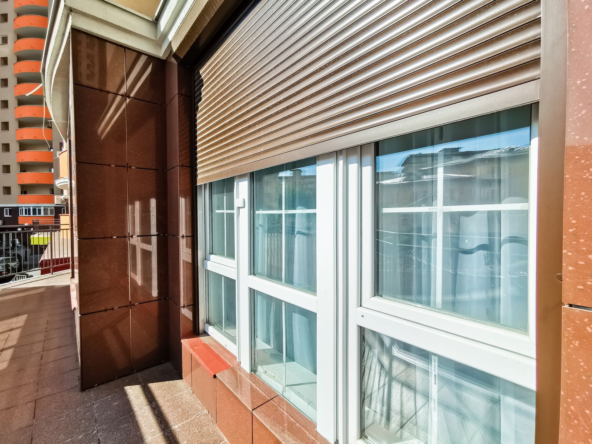 Exterior windows fitted with metal roller shutters on a modern residential building balcony. Exterior windows fitted with metal roller shutters on a modern residential building balcony.